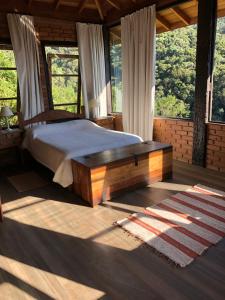 a bedroom with a bed in a room with windows at Sítio Mutandis in Itamonte