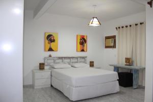 a white bedroom with a bed and a table at Condominio Sao Cristovao in Santa Cruz Cabrália