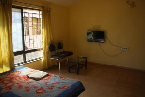 1 dormitorio con 1 cama y TV en la pared en Purvaj Vastalya, en Kolhapur