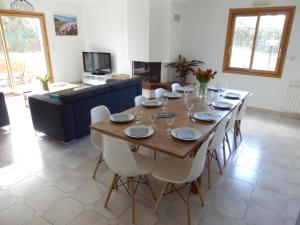 una sala da pranzo con tavolo in legno e sedie bianche di Villa à la croisée des baies a Tréméoc