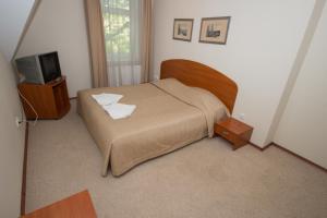 Deims Hotel في سيلوت: غرفة نوم صغيرة بها سرير وتلفزيون