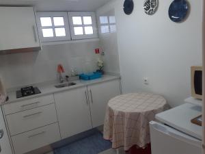 uma cozinha com armários brancos, um lavatório e uma mesa em Apartamento Piquinho em Machico