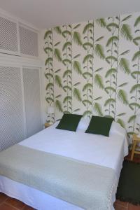 a bedroom with a white bed with green leaves on the wall at Azul Sul in Tavira