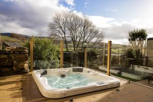 a jacuzzi tub sitting on top of a wooden deck at Finest Retreats - Tegannedd - Luxury Grade II Listed Cottage With Hot Tub in Ffestiniog