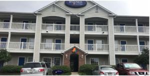 InTown Suites Extended Stay Columbia SC - Columbiana في كولومبيا: عمارة سكنية كبيرة فيها سيارات تقف امامها