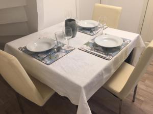 Biały stół z dwoma talerzami i kieliszkami do wina w obiekcie Extraordinary apartment with double shower w mieście Norrahammar