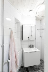 La salle de bains blanche est pourvue d'un lavabo et d'un miroir. dans l'établissement Home Studio Maria, à Helsinki