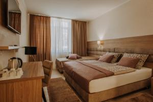 a hotel room with two beds and a desk at Villa Martini - apartments & rooms in Vukovar