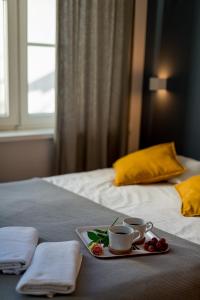 ソポトにあるSopot Loftのベッドの上にコーヒーカップ2つと花を用意したトレイ
