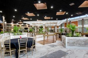 a restaurant with tables and chairs and plants at LeBossier Hotel in Bossier City