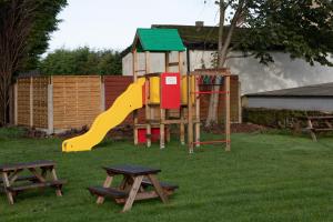 um parque infantil com escorrega e duas mesas de piquenique em Plough Inn em Morpeth