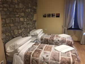 2 camas en una habitación con una pared de piedra en Residence La Canonica, en Costa Valle Imagna