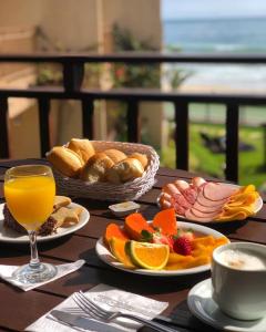 een tafel met borden en een glas sinaasappelsap bij Morada do Mar Hotel in Bombinhas