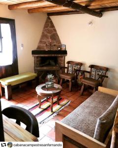 a living room with a fireplace and a table and chairs at Cabaña Campestre San Fernando in Iza