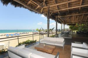 eine Terrasse des Resorts mit weißen Möbeln und Strand in der Unterkunft Blue JackTar in San Felipe de Puerto Plata