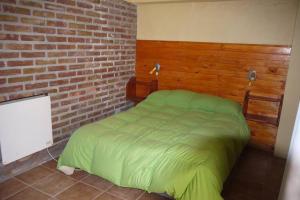 una camera con un letto verde con un muro di mattoni di SOL PATAGONICO a Playas Doradas