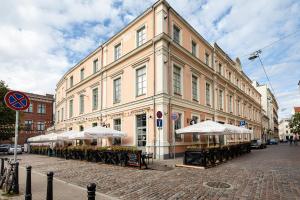 a large building with tables and umbrellas on a street at Old Riga Two floor Palasta Loft Apartment with river view in Riga