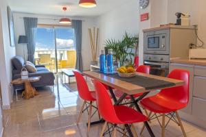 kuchnia z drewnianym stołem i czerwonymi krzesłami w obiekcie La Perla Beach Apt with Pool w mieście El Médano