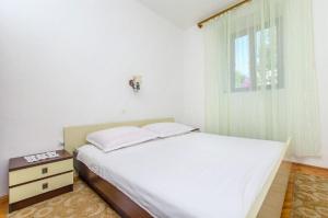 a bedroom with a white bed and a window at Apartments Jerkica - 50 m from sea in Sutivan