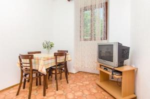ein Esszimmer mit einem Tisch mit Stühlen und einem TV in der Unterkunft Apartments Jerkica - 50 m from sea in Sutivan