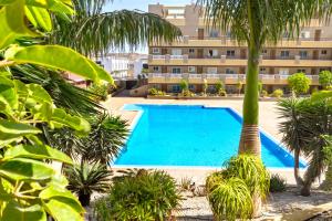 basen przed budynkiem z palmami w obiekcie La Perla Beach Apt with Pool w mieście El Médano