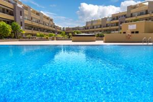 duży basen przed niektórymi budynkami apartamentowymi w obiekcie La Perla Beach Apt with Pool w mieście El Médano