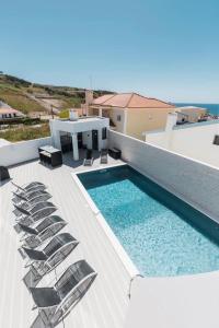 a swimming pool on the roof of a house with chairs at EDEN VILLA in Casal do Cigano