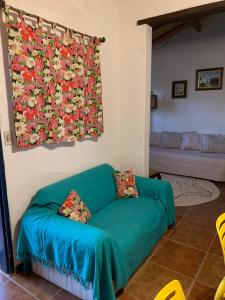 um sofá verde numa sala de estar com uma cortina de flores em Chalés na fazenda em Santo Antônio de Posse