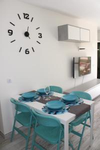 a dining room table with chairs and a clock on the wall at Solymar Las Olas in Playa del Ingles