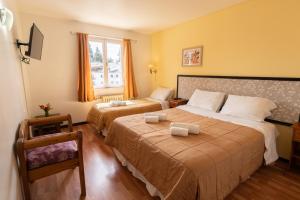 a hotel room with two beds and a window at Hosteria La Pastorella in San Carlos de Bariloche