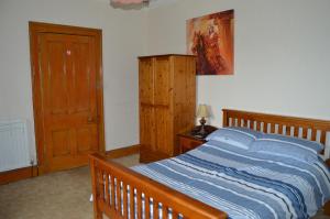 a bedroom with a bed with a wooden bed frame at Carnegie Holiday Cottage in Dunfermline