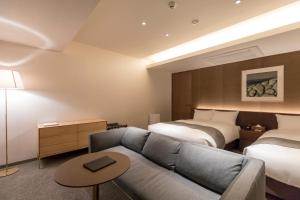 a hotel room with two beds and a couch at yoin hotel kyoto gion in Kyoto