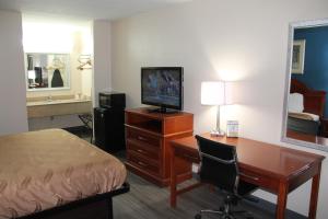 Habitación de hotel con escritorio, cama y TV en Americas Best Value Inn Tuscaloosa en Tuscaloosa