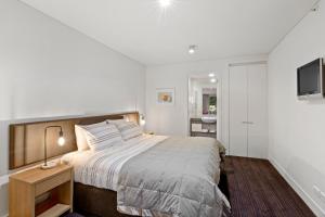 1 dormitorio con 1 cama grande y TV en Lakefront Marina Apartment, en Queenstown