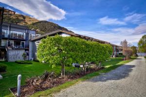 a house with a tree in front of a street at Lakefront Marina Apartment in Queenstown