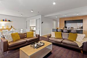 a living room with two couches and a table at Lakefront Marina Apartment in Queenstown