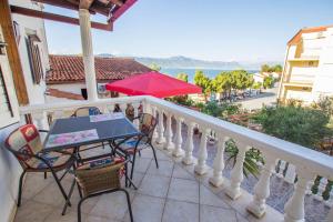 a balcony with a table and chairs and an umbrella at Apartments David - 20m from the beach with parking in Trogir