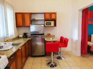 una cucina con frigorifero in acciaio inossidabile e sedie rosse di Studio Apartments in Las Torres a Coco