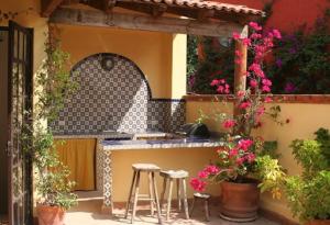 an outdoor kitchen with stools and a counter with flowers at Casa de la Mañana in San Miguel de Allende