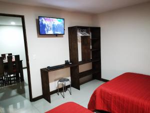 1 dormitorio con 1 cama y TV en la pared en CASA GERANIOS # 2, en Monteverde