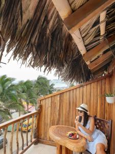 kobieta siedząca przy stole na balkonie w obiekcie Cocoa Inn Hostal w mieście Canoa