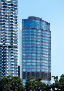 香港Oasis Aurum 181 Hotel的一座高大的玻璃建筑,前面有树木