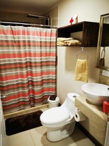 uma casa de banho com um WC, um lavatório e uma cortina de chuveiro em CASA GERANIOS STUDIO #3 em Monteverde