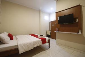 Un dormitorio con una cama y un televisor de pantalla plana. en RedDoorz Plus @ Jalan Parangtritis 2, en Yogyakarta
