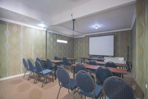 a conference room with tables and chairs and a screen at RedDoorz Plus near Alun Alun Kuningan in Kuningan