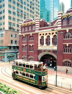 a green double decker bus driving past a building at Butterfly on Wellington, Central in Hong Kong