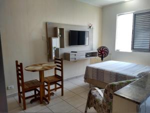 Kleines Zimmer mit einem Bett, einem Tisch und einem TV. in der Unterkunft Edifício Lord - APTO in São Vicente