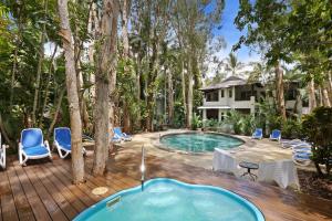 a hot tub on a deck with chairs and a house at The Reef Retreat Palm Cove in Palm Cove