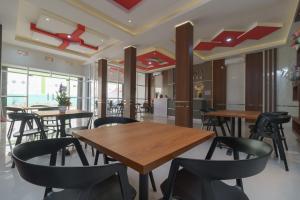 un restaurant avec des tables en bois et des chaises noires dans l'établissement RedDoorz Plus at Grand Tara Homestay Palembang, à Palembang