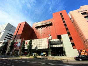 een rood gebouw in een stadsstraat met gebouwen bij WeBase TAKAMATSU in Takamatsu